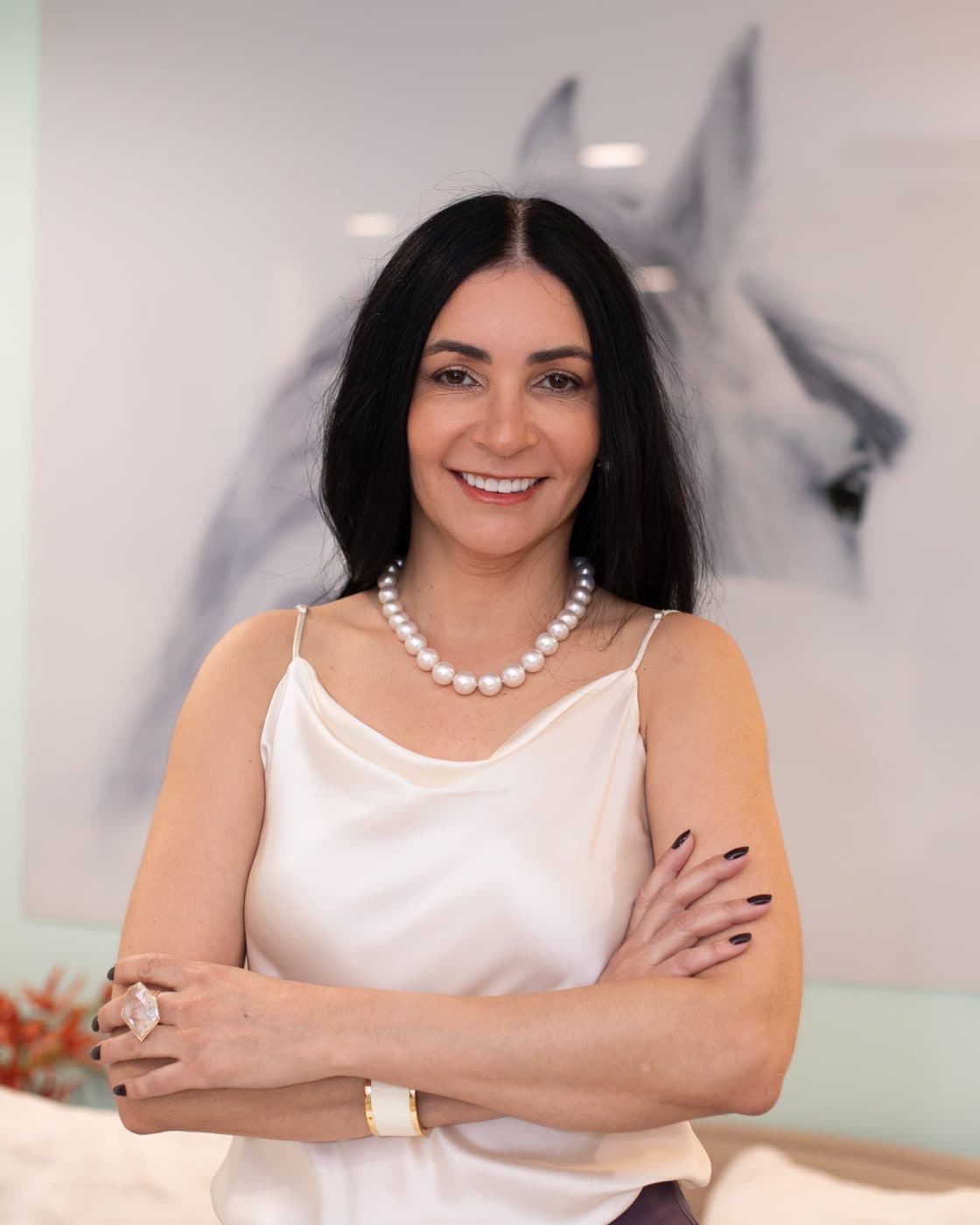 Silvana Buranek, founder of LIVBO, in a silk top and pearls, arms crossed, smiling at the camera.